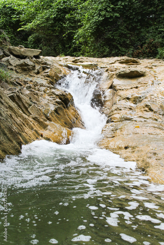 Fototapeta premium Mountain waterfall. Stone coast. Waterfall in the forest.
