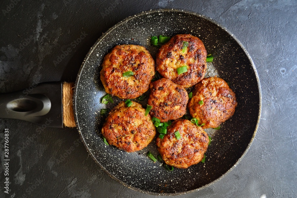 Meat cutlets. Cutlets in a pan on a black concrete table background. Delicious tasty food. Cutlets in the black plate isolated.