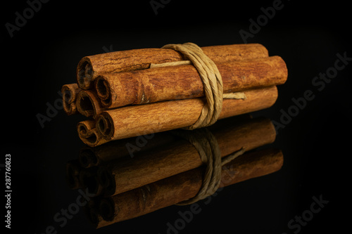Slika na platnu Group of six whole dry brown cinnamon wrapped in natural twine isolated on black