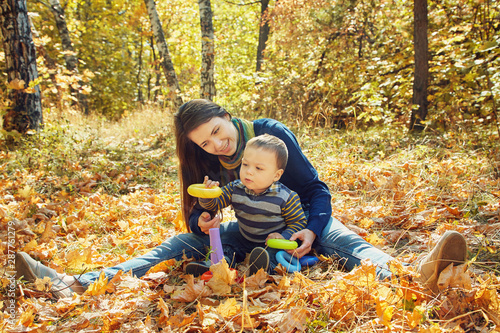 developing game playing young mother with her baby outdoors. Mom and son in an autumn park.