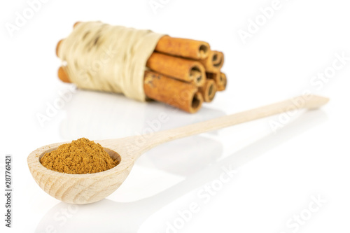 Group of six whole dry brown cinnamon wrapped in natural bast in a wooden spoon isolated on white background