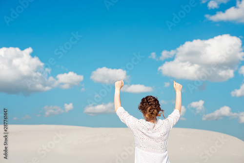 Confident young woman raising her fist up in the sky. Feeling motivated.