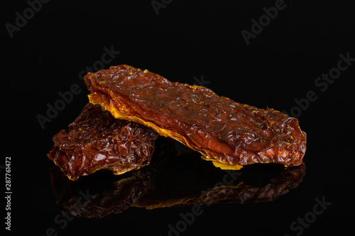 Group of two whole dried red tomato isolated on black glass