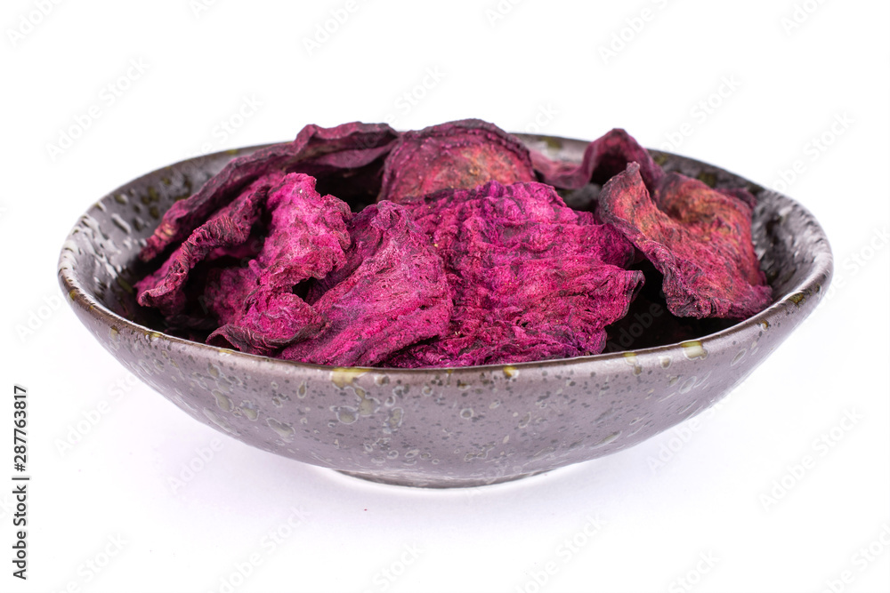 Obraz premium Lot of slices of dried red beetroot in dark ceramic bowl isolated on white background