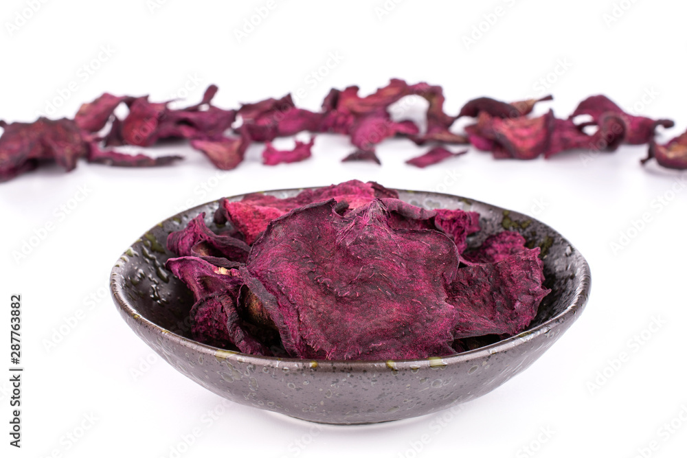 Obraz premium Lot of slices of dried red beetroot in dark ceramic bowl isolated on white background