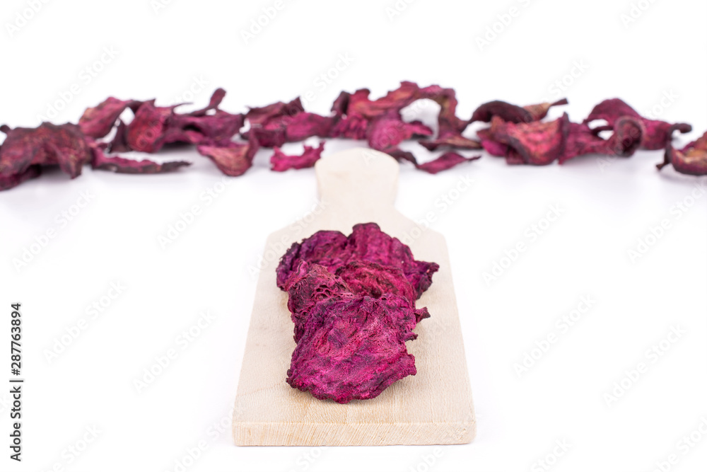 Obraz premium Lot of slices of dried red beetroot on small wooden cutting board isolated on white background