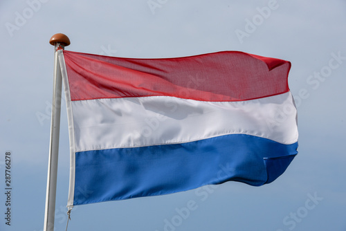 Dutch flag waving against blue sky