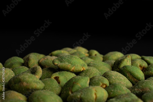 Lot of whole spicy green wasabi peanut isolated on black glass