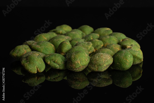 Lot of whole spicy green wasabi peanut in a large group isolated on black glass