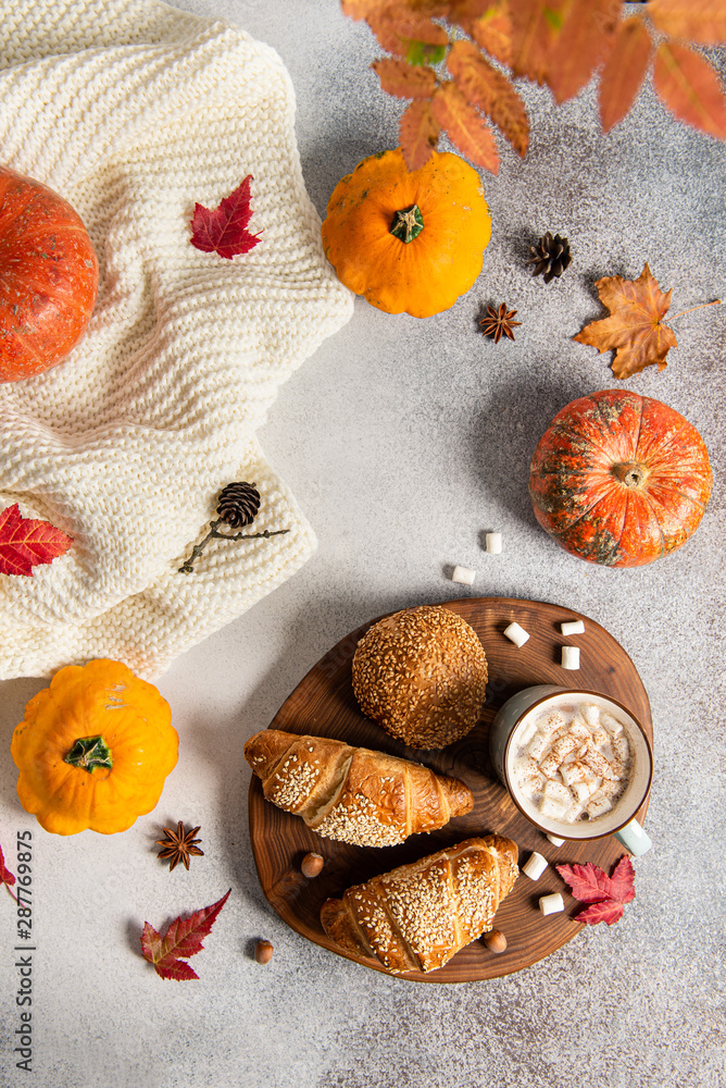 Autumn flat lay composition. Mug of hot cocoa, croissant, pumpkins and autumn leaves on grey background. Cozy autumn concept. Autumn flat lay composition. Mug of hot cocoa, croissant, pumpkins and autumn leaves on grey background. Cozy autumn concept.
