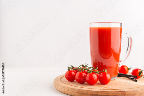Fresh Tomato juice in a Cup on a wooden tray with cherry tomatoes