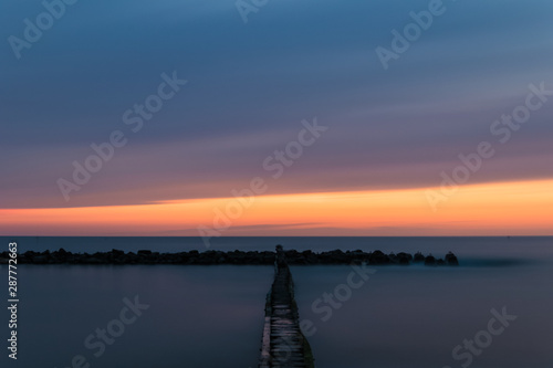 Long exposure image. Landscape of the waterbreak in the sea under the sky during sunset. photo