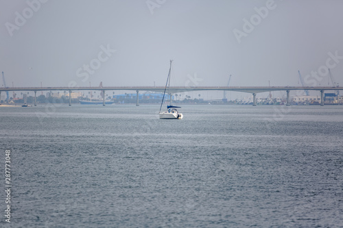View of Aveiro river with private recreational boat with people sailing. Day with clouds and background with bridge