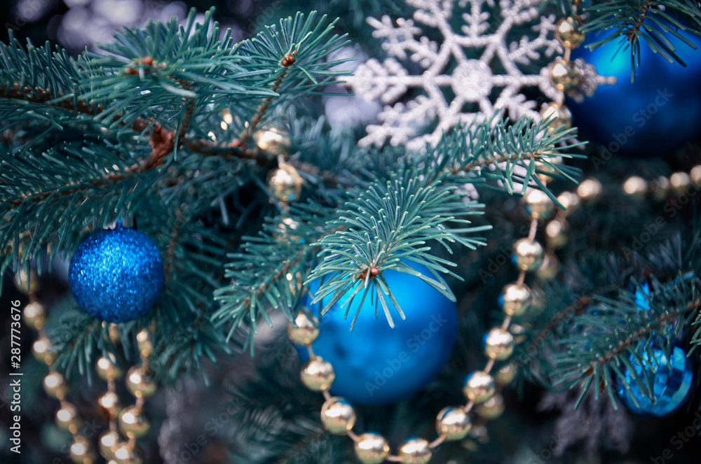 close-up of a Christmas tree with rose gold and turquoise decorations (balls, snowflakes, bows, beads) on a blurry background with snow. Christmas and New Year holidays background close-up of a Christmas tree with rose gold and turquoise decorations (balls, snowflakes, bows, beads) on a blurry background with snow. Christmas and New Year holidays background