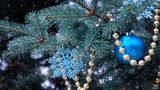 close-up of a Christmas tree with rose gold and turquoise decorations (balls, snowflakes, bows, beads) on a blurry background with snow. Christmas and New Year holidays background
