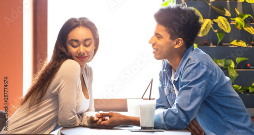 Black guy telling good words his flattered girlfriend photo