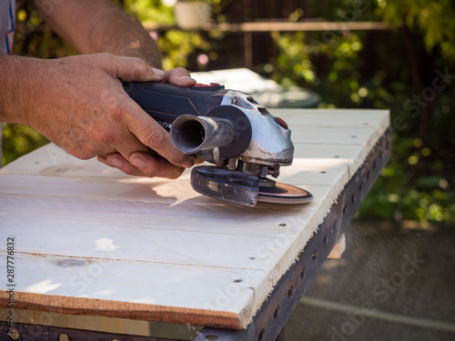 Man working with angle grinder and flap disc as a Sander on wooden shelf Fototapete