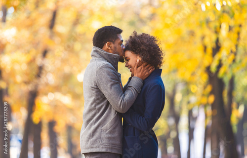 Afro man kissing his girlfriend forehead while walking © Prostock-studio