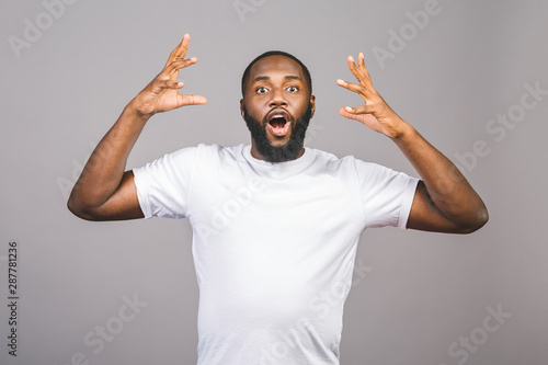 Young african american man very happy and excited, winner expression celebrating victory screaming with big smile and raised hands isolated againt grey background.