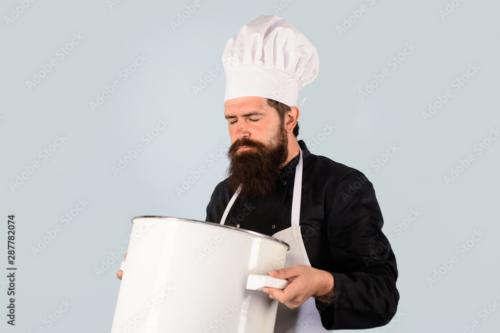 Chef with big casserole or saucepan. Professional cookery concept. Man with beard hold kitchenware. Cooking process concept. Kitchen tool. Utensil. Male cook in uniform. Cook in white apron holds pot. Chef with big casserole or saucepan. Professional cookery concept. Man with beard hold kitchenware. Cooking process concept. Kitchen tool. Utensil. Male cook in uniform. Cook in white apron holds pot.