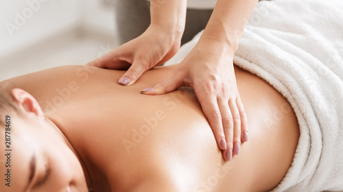 Body care. Young girl having massage  relaxing in spa salon