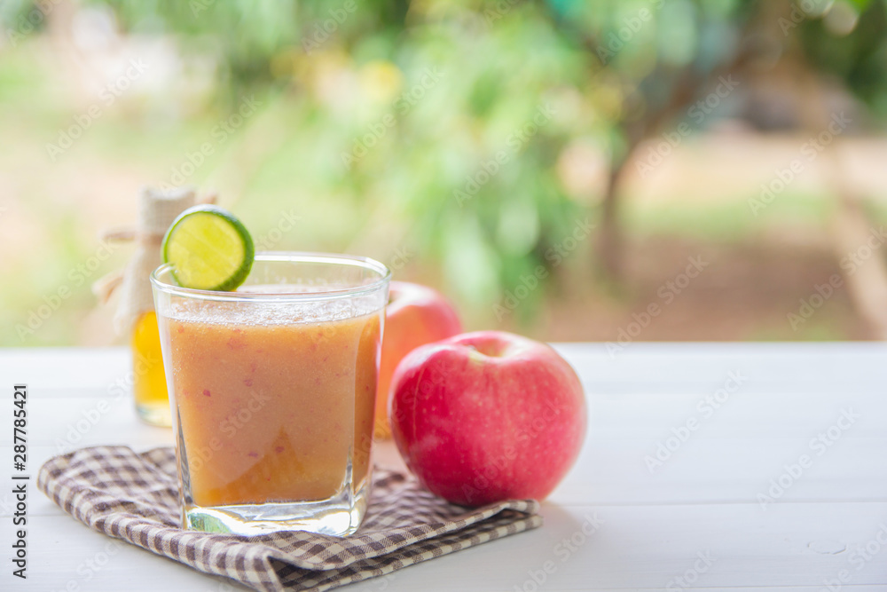 Fototapeta premium Healthy drink,Reduce cholesterol in the blood vessels of smoothies with red apple and lemon, Honey bottle in a glass on white wooden background