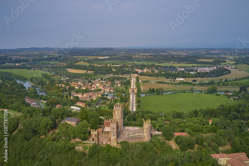 Castello scaligero in the town of Valeggio sul Mincio. The historic Ponte Visconteo Bridge was built in 1395 on the Mincio River. Aerial view. Flying on drone.