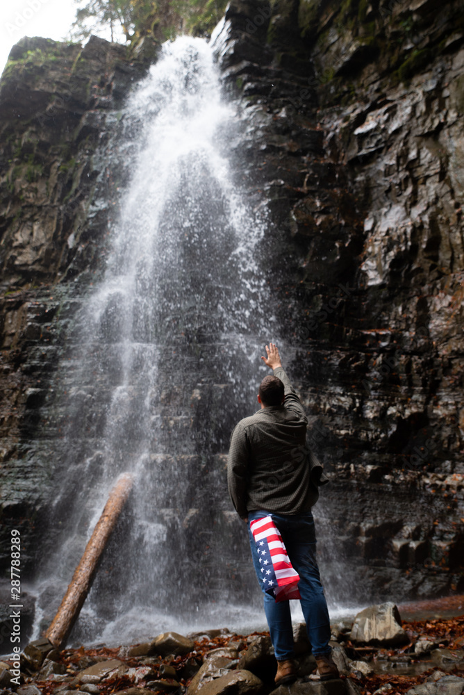 man looking at waterfall autumn hiking concept