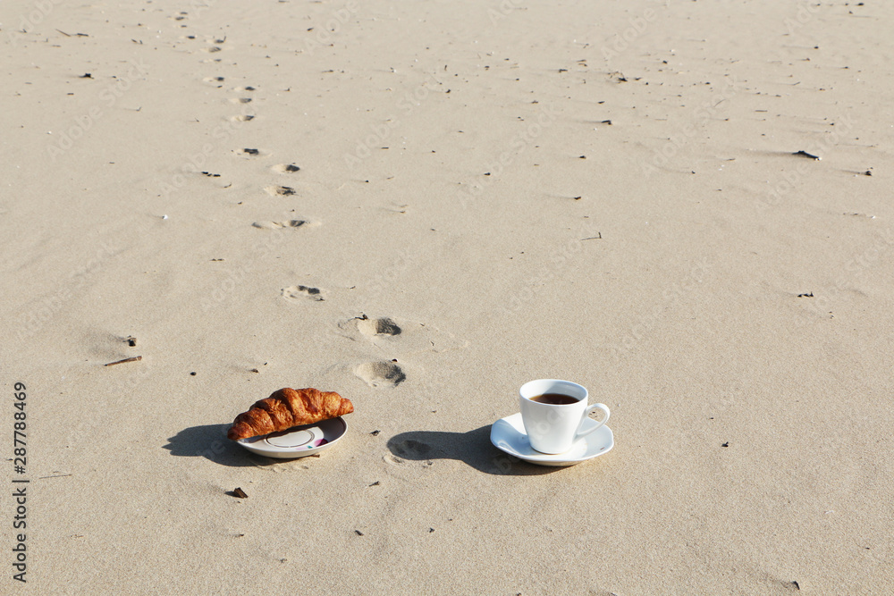 Obraz premium A cup of coffee stands on the sandy seashore