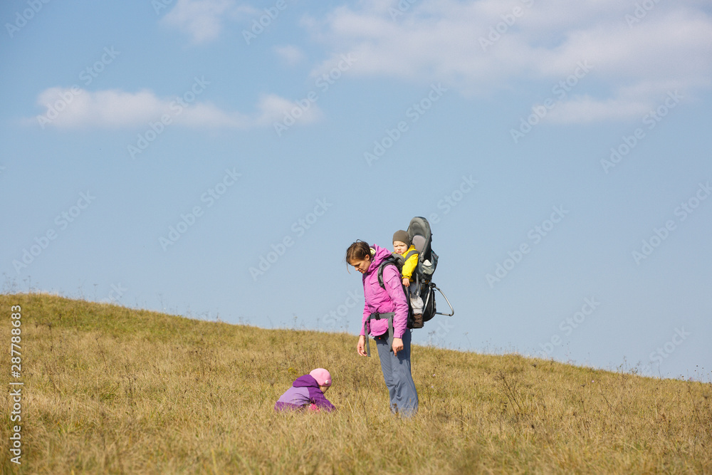 Mother with children hiking on a nice autumn day carrying kid Mother with children hiking on a nice autumn day carrying kid