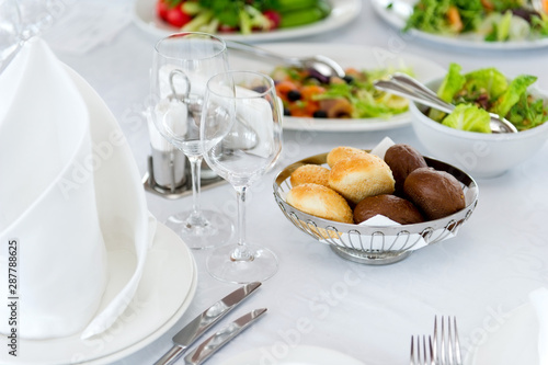 buns of white and black bread on a served table on a background of salads