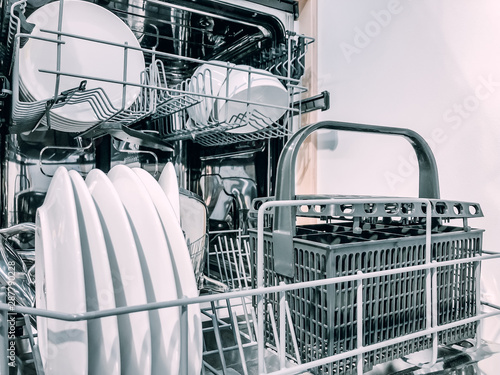 Open dishwasher machine with white clean dishes