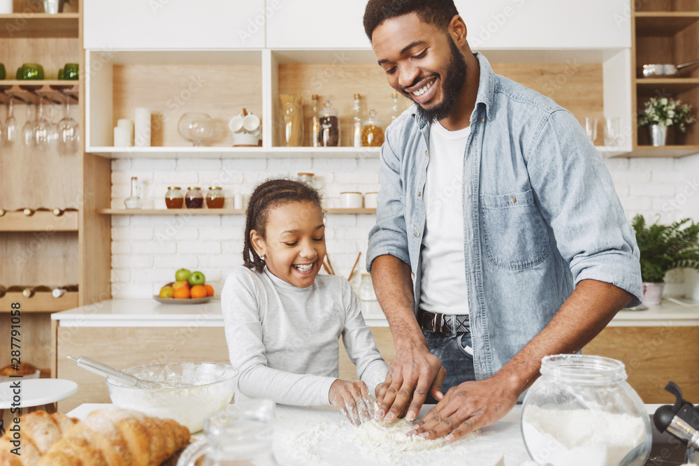 Happy african american family playing with dough while cooking