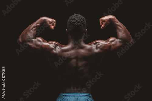Athletic african american male bodybuilder flexing muscles