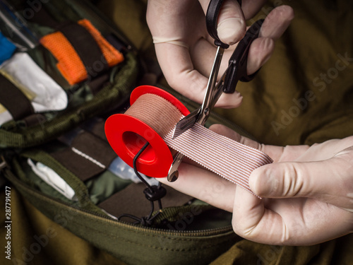 Medical tape cutting during first aid in an emergency. Hands in latex gloves holding trauma shears