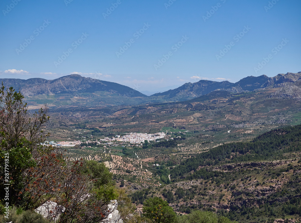 El Burgo Town, seen from a Viewpoint high up in the Sierra de las Nieves National Park, set amongst the Olive Groves in the Valley Floor. Spain