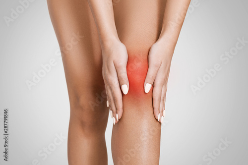 Woman massaging her sore injured knee, closeup