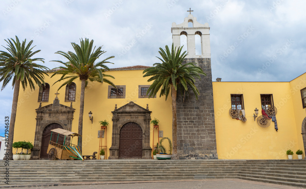 Main Square In Garachico With Monastery Of San Francisco, Tenerife, Spain and folk decoration. Palms in a facade from a historic building