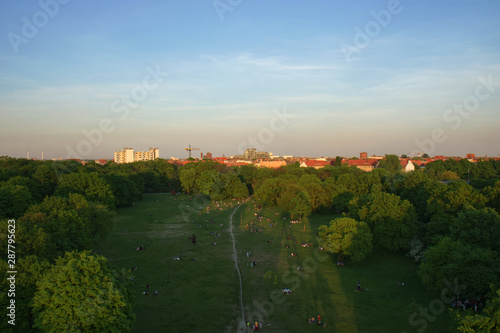 Aerial View of Berlin Park Hasenheide in Kreuzberg on an Spring afternoon with people relaxing and having fun on a large meadow in the sun. Behind the trees you can see roof tops of Berlin