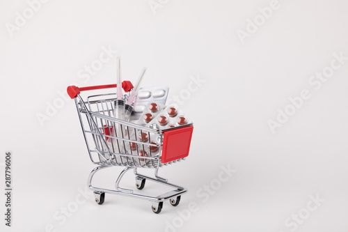 shopping cart loaded with syringes and drugs, isolated on white background, copy space