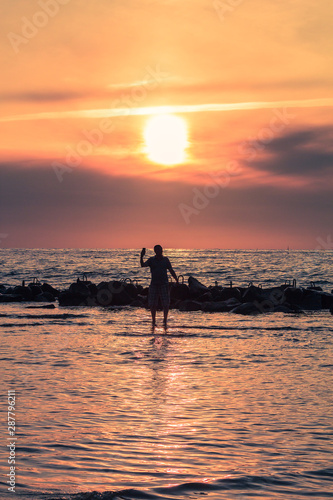 One man making  a sselfie in the sea during sunset