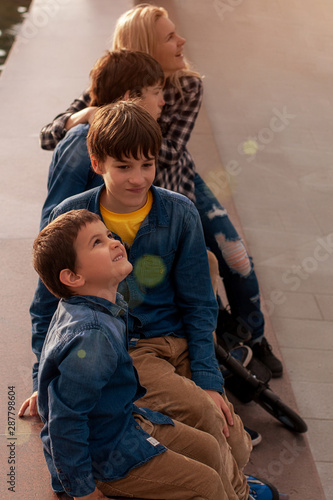 Mom with three children in the park. Two twin teens and a 5 year old boy. Look at interesting things. Training. A comfortable pastime with family. photo