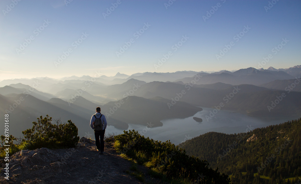 wanderer at mountain Herzogstand and lake Walchenseein early morning 