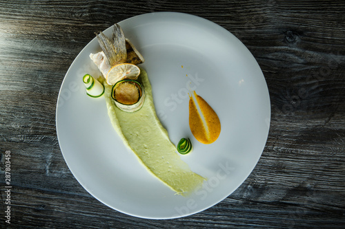 Fotografia top view on exquisite decorated fish roll with garnish on white dish