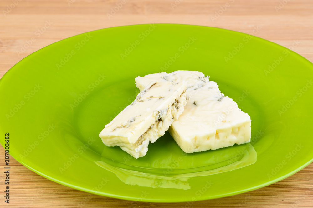 Pieces of blue cheese on a green plate.