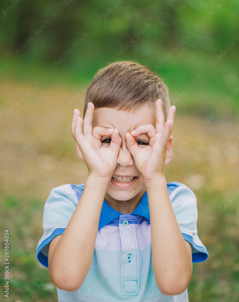 Closeup view of cute white little boy playing outdoor in summer meadow, Kid making binocular or eyeglasses gesture using his fingers. Vertical color photography. Closeup view of cute white little boy playing outdoor in summer meadow, Kid making binocular or eyeglasses gesture using his fingers. Vertical color photography.