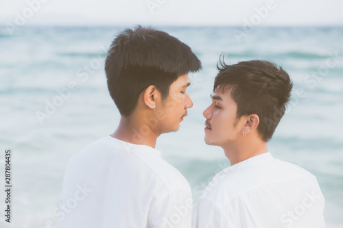 Back view homosexual asian couple standing together on beach in summer, asia gay holding hands going sea for leisure and relax with romantic and happy in vacation at sea, LGBT with legal concept. © N_studio