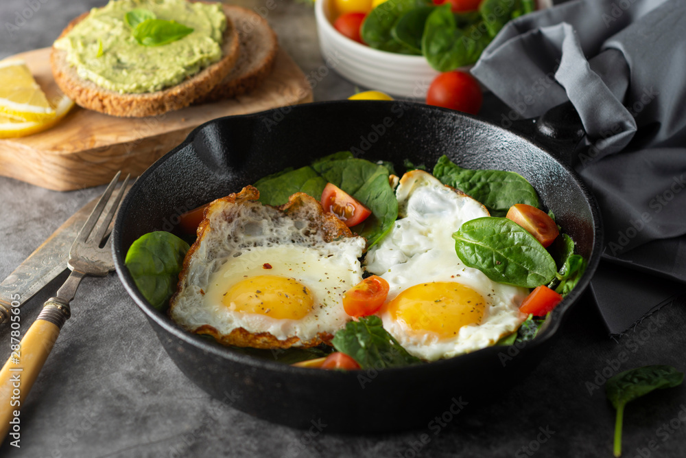 Fried sunny eggs with spinach, avocado toast and fresh tomatoes. healthy breakfast food. Fried sunny eggs with spinach, avocado toast and fresh tomatoes. healthy breakfast food.