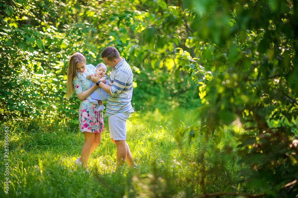 Fototapeta premium Happy young family is relaxing outdoors. Walk in the park with a child in her arms. having fun