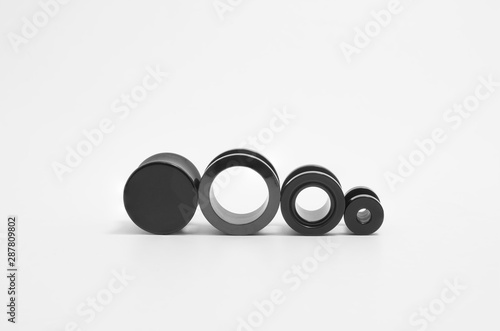 Black ear stretchers: ear tunnels and plug on white background. Varied types, and sizes.